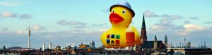 Photo Montage of the typical München Duck with beer over the city of Munich