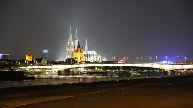 The cathedral in Cologne seen from the Rhine at night time with glowing lights